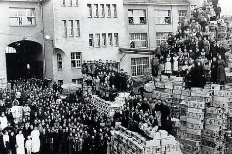 Die Belegschaftsmitglieder der Frankonia AG sitzen im Hof auf Handgranatenkisten. 30.000 Stück wurden am Tag hergestellt.